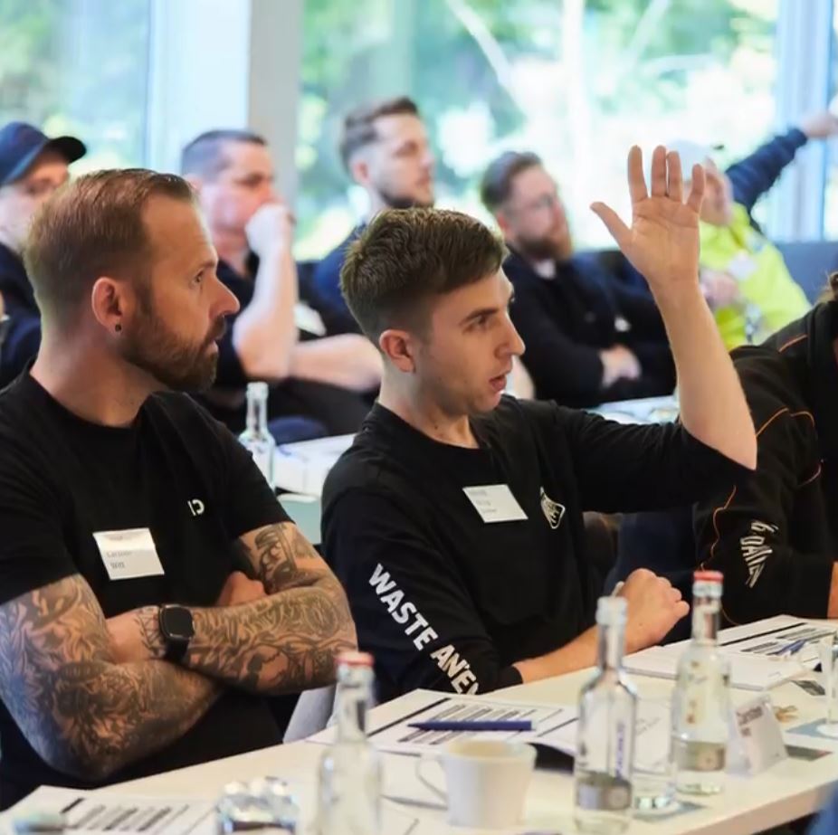 Teilnehmerinnen und Teilnehmer der Lockout/Tagout Mastery Class diskutieren aktiv während einer Schulung in einem modernen Seminarraum.